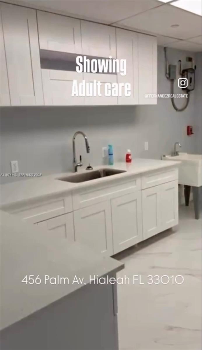 A kitchen area features white shaker cabinets, a stainless steel sink, and light-colored countertops — Palm Ave, Hialeah FL 33010, HIALEAH, FL
