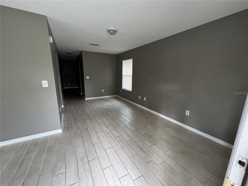 An empty room features gray walls, light-colored wood-look tile flooring, and a single window — 717 W SILVER SPRINGS PLACE, OCALA, FL