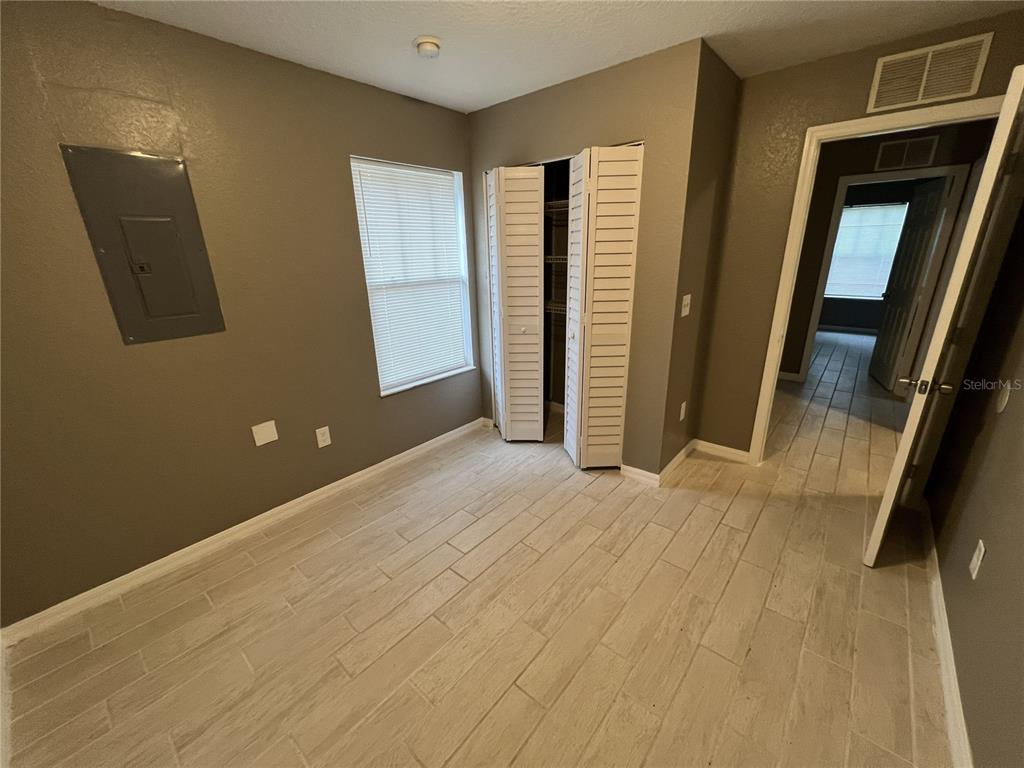 A bedroom with light wood-look tile flooring, a closet with louvered doors, and gray walls — 717 W SILVER SPRINGS PLACE, OCALA, FL