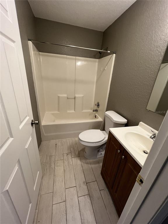A bathroom features a white tub-shower combo, a toilet, and a wood vanity with sink — 717 W SILVER SPRINGS PLACE, OCALA, FL