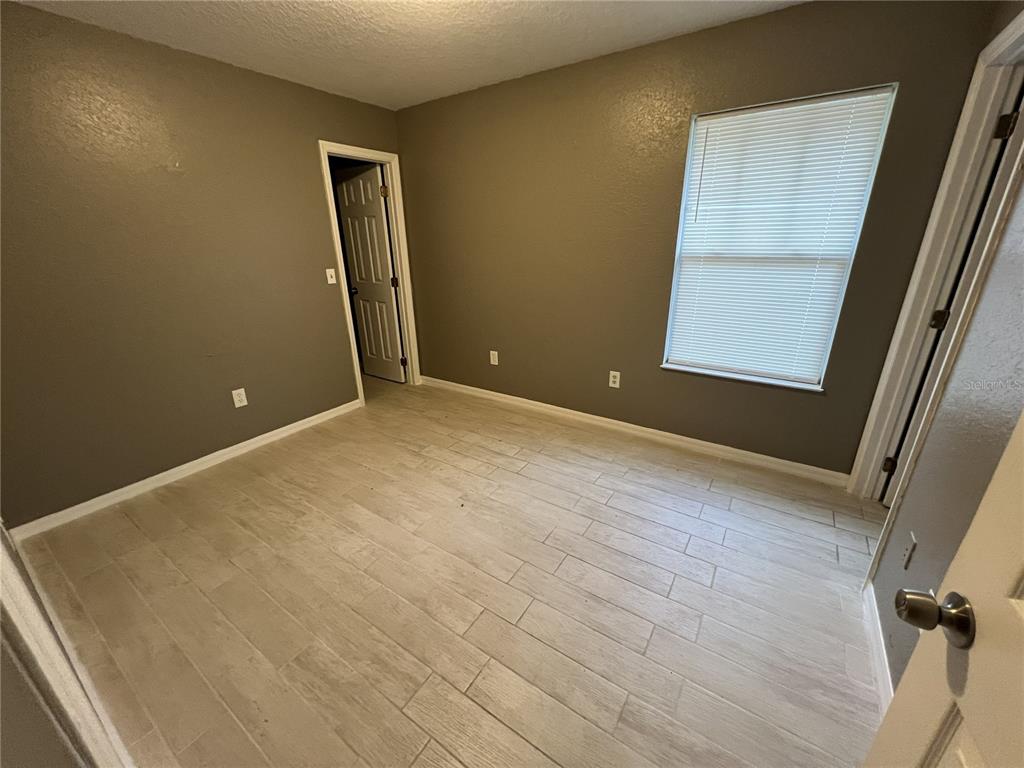 An empty bedroom features gray walls, light wood-look tile flooring, and a single window — 717 W SILVER SPRINGS PLACE, OCALA, FL
