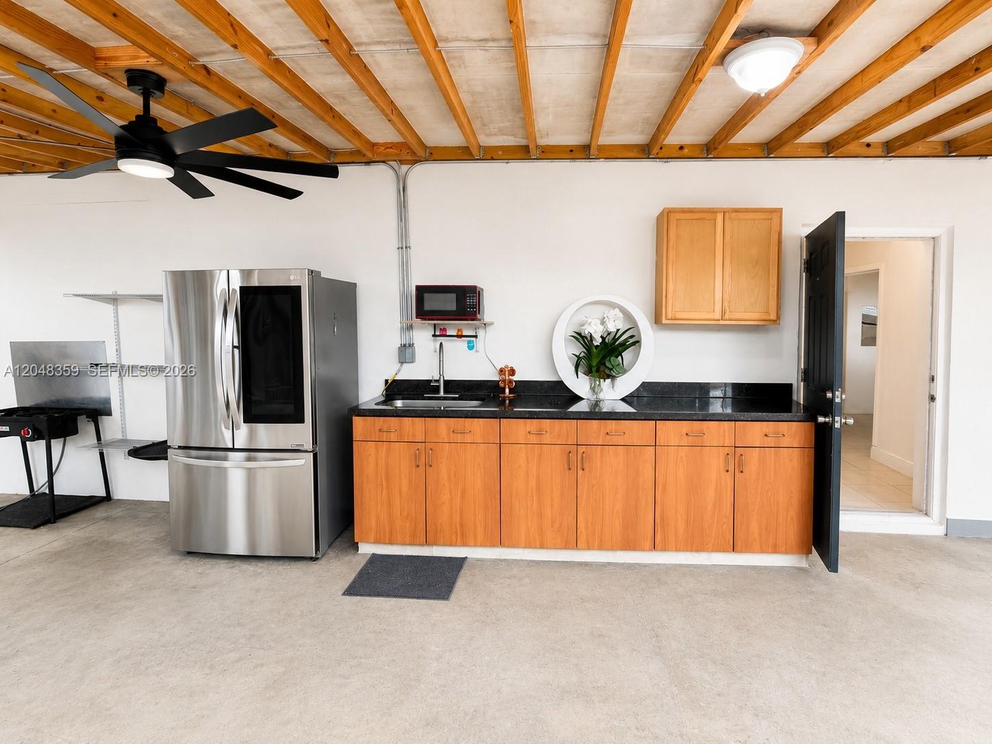 A garage space features a kitchenette with wood cabinets, a stainless refrigerator, and exposed beams — 621 E 52nd St, Hialeah FL 33013, HIALEAH, FL