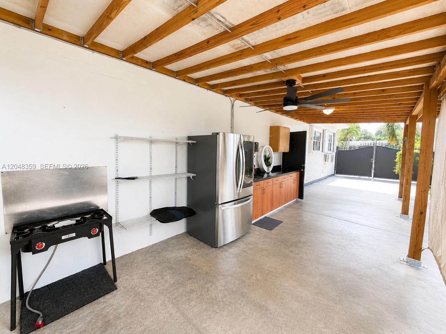 An outdoor kitchen area features a stainless steel refrigerator, wooden cabinets, and a portable stove — 621 E 52nd St, Hialeah FL 33013, HIALEAH, FL