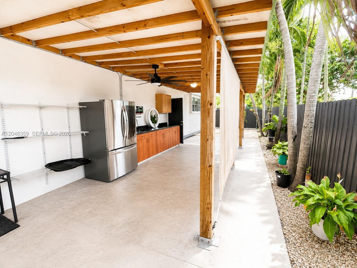 An outdoor kitchen area features a stainless steel refrigerator, wooden cabinets, and a covered patio — 621 E 52nd St, Hialeah FL 33013, HIALEAH, FL