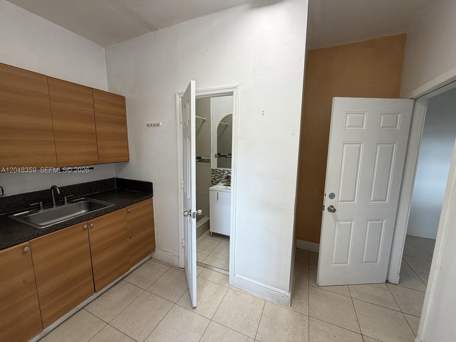 A small kitchen area features wood-grain cabinets, a dark countertop, and an adjacent bathroom door — 621 E 52nd St, Hialeah FL 33013, HIALEAH, FL