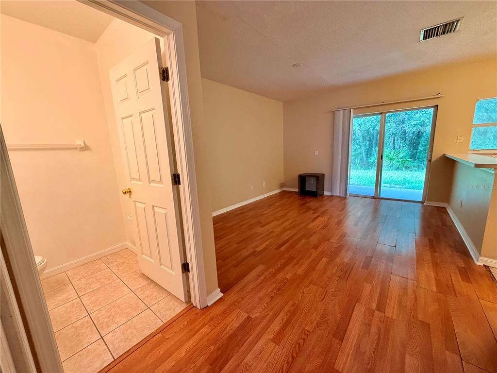 An interior view showing a room with wood flooring, a sliding glass door, and bathroom — 30209 SWINFORD LANE, WESLEY CHAPEL, FL