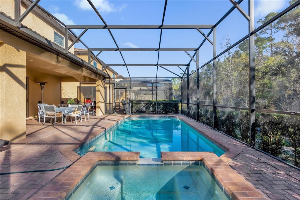 A screened-in patio features a swimming pool, a raised spa, and a dining area — 8824 BENGAL COURT, KISSIMMEE, FL