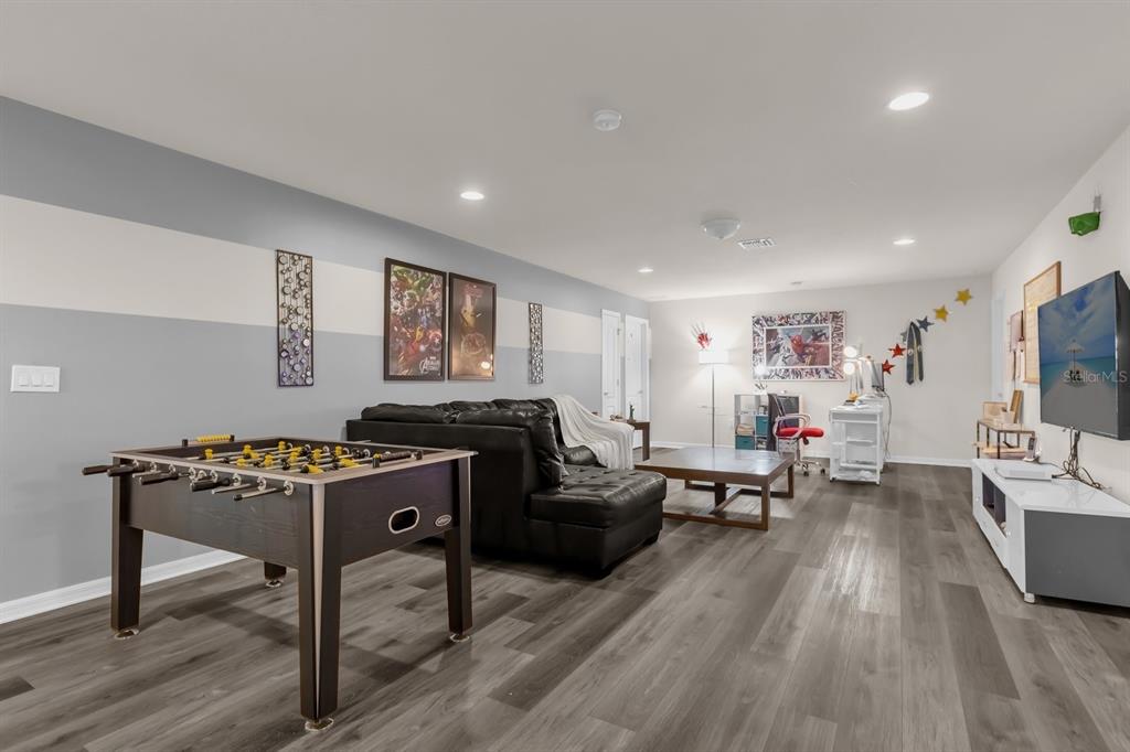 A game room features a foosball table, a black leather sofa, and a television console — 8824 BENGAL COURT, KISSIMMEE, FL