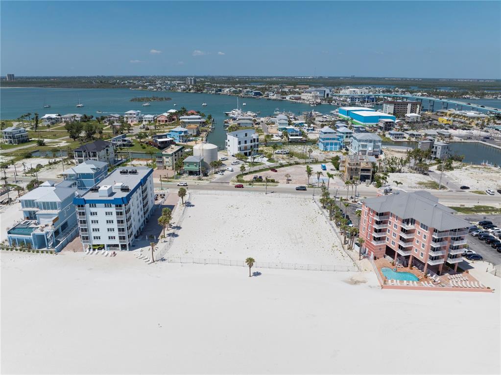 An aerial view shows a vacant sandy lot situated between two multi-story buildings near water — 800-802 ESTERO BOULEVARD, FORT MYERS BEACH, FL