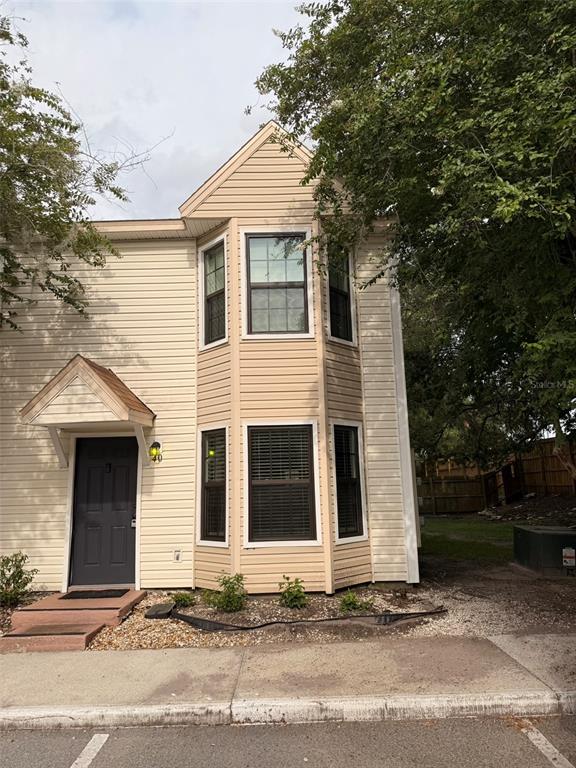 A two-story tan vinyl-sided townhouse with a dark front door and bay windows — 2302 MAKI ROAD UNIT 40, PLANT CITY, FL
