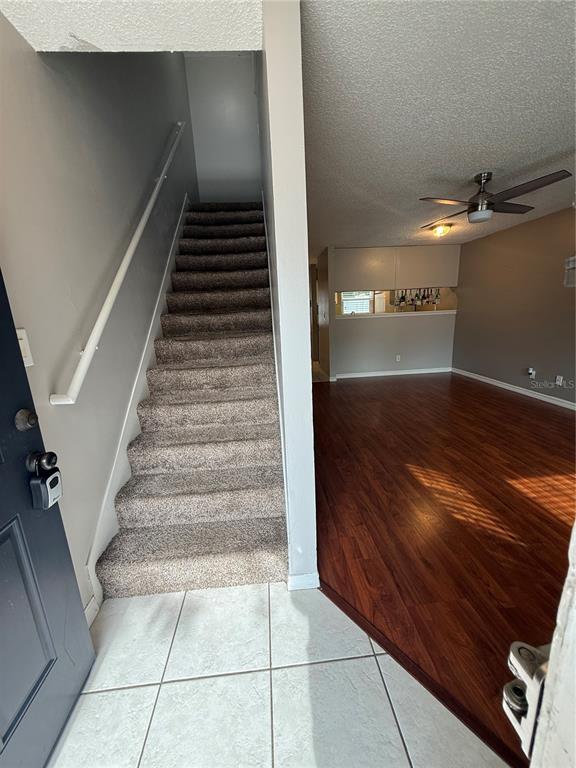 An entryway with tiled flooring leads to carpeted stairs and a living room with wood floors — 2302 MAKI ROAD UNIT 40, PLANT CITY, FL