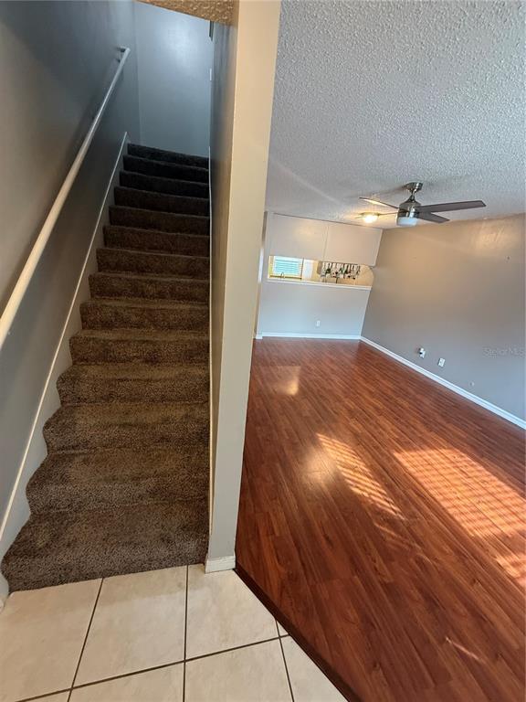 A carpeted staircase leads upward next to a living area with wood-look flooring — 2302 MAKI ROAD UNIT 40, PLANT CITY, FL