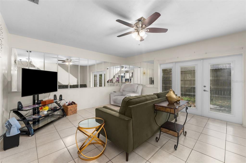 A living room features a green sofa, a television on a stand, and mirrored walls — 3312 NW 52ND TERRACE, GAINESVILLE, FL