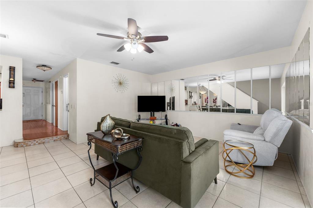 A living room features a green sofa, a recliner, tiled floors, and a mirrored wall — 3312 NW 52ND TERRACE, GAINESVILLE, FL