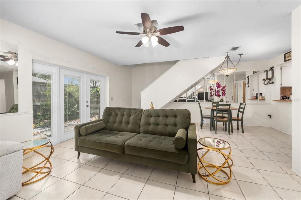 A living room with a green sofa, tile floors, and a dining area under stairs — 3312 NW 52ND TERRACE, GAINESVILLE, FL