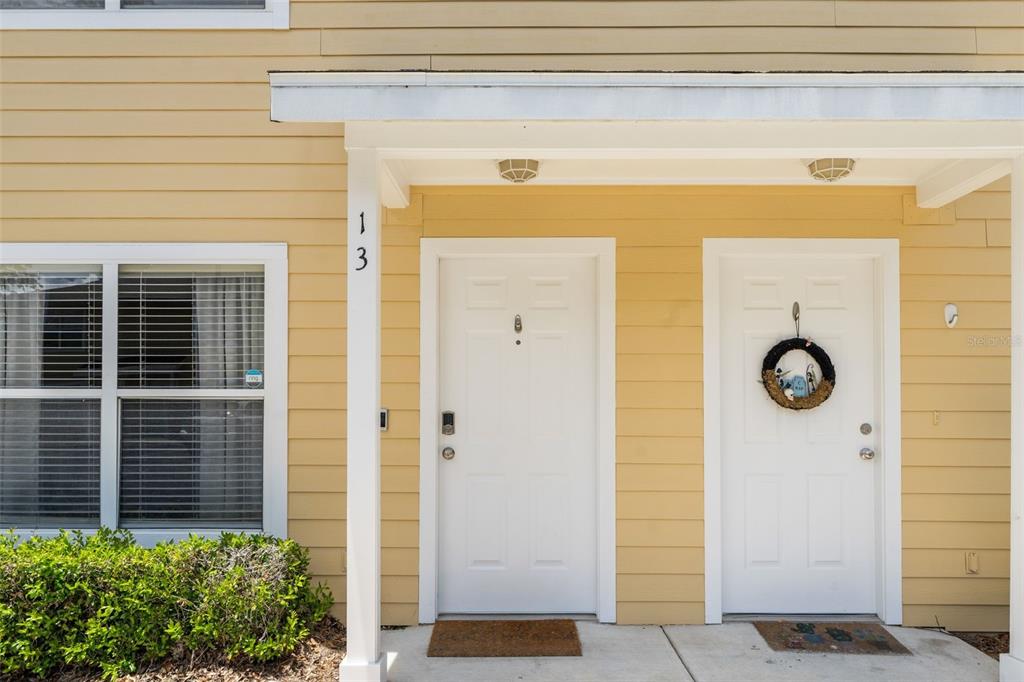 The exterior of a yellow building features two white front doors under a covered porch — 2636 SW 35TH PLACE UNIT 13, GAINESVILLE, FL