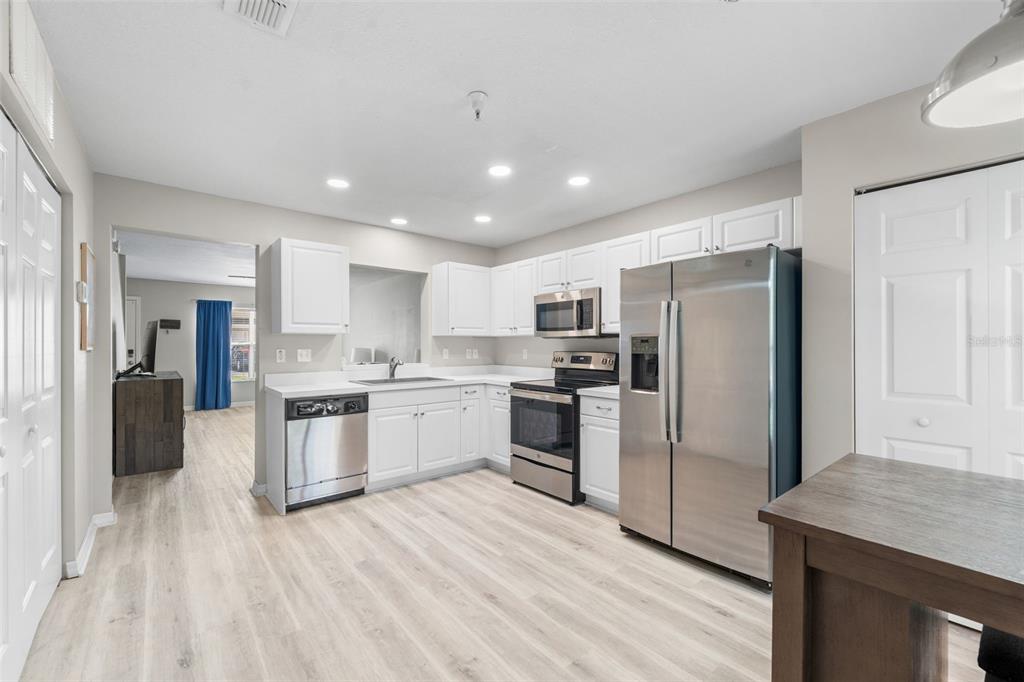 A kitchen with white cabinets, stainless steel appliances, and light wood-look flooring — 2636 SW 35TH PLACE UNIT 13, GAINESVILLE, FL