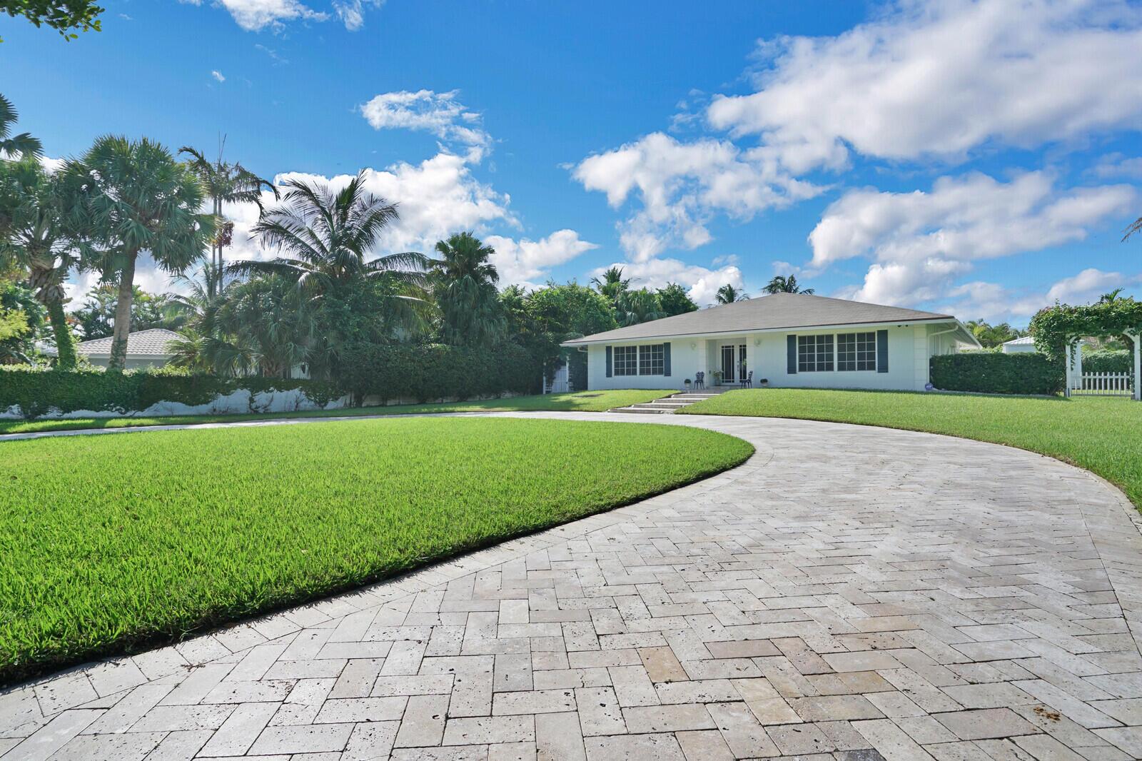 A white single-story house features a curved stone paver driveway and a large front lawn — 17 E Ocean Avenue, Ocean Ridge FL 33435, OCEAN RIDGE, FL