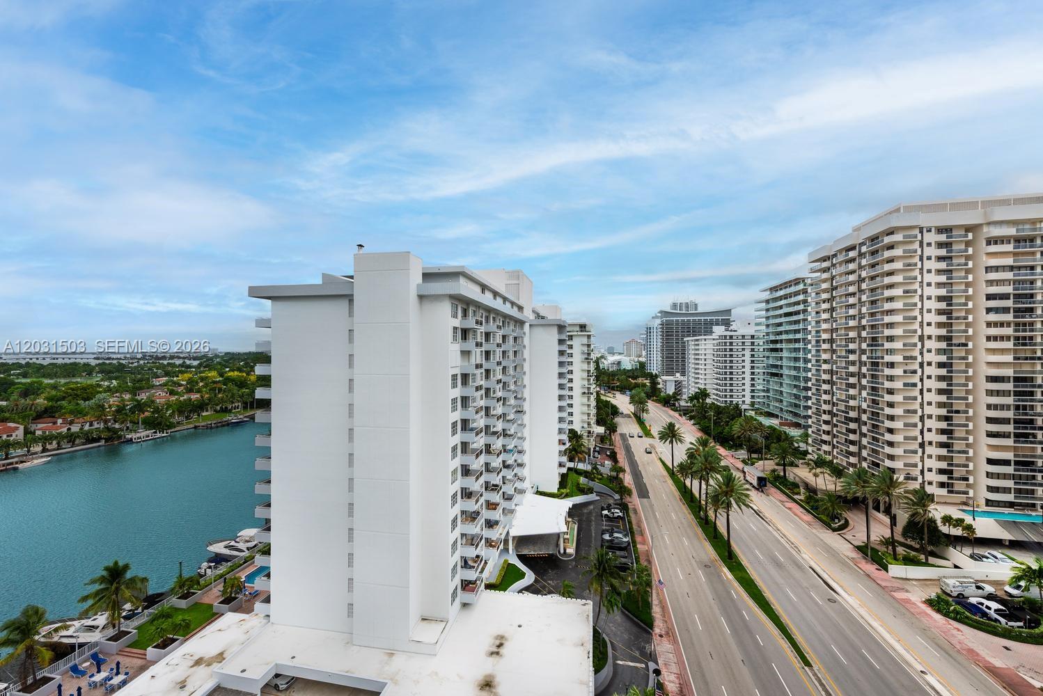 An aerial view shows a tall white apartment building beside a canal and a road — 5660 Collins Ave # 14C, Miami Beach FL 33140, MIAMI BEACH, FL