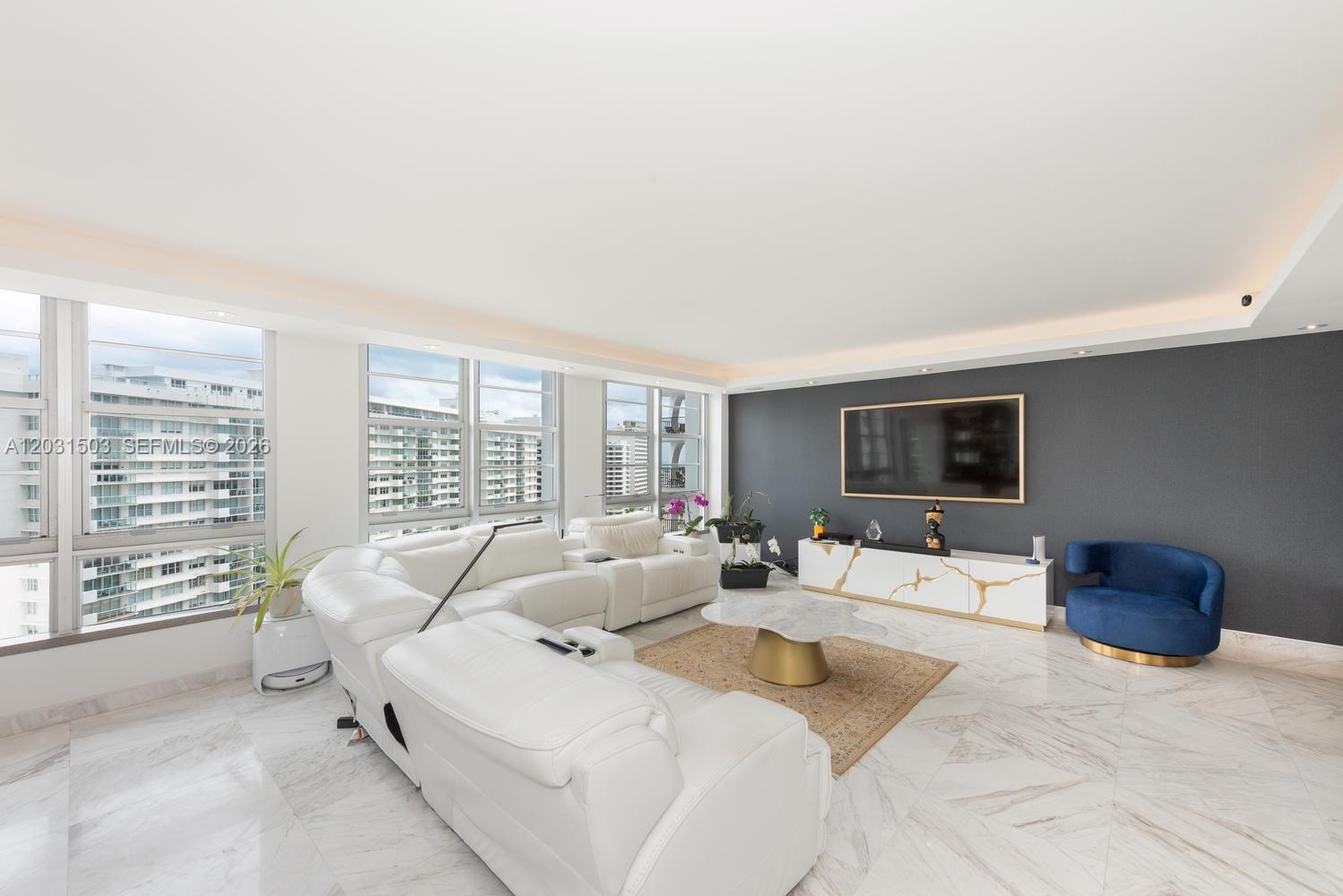 A living room features a white sectional sofa, marble floors, and a dark accent wall — 5660 Collins Ave # 14C, Miami Beach FL 33140, MIAMI BEACH, FL