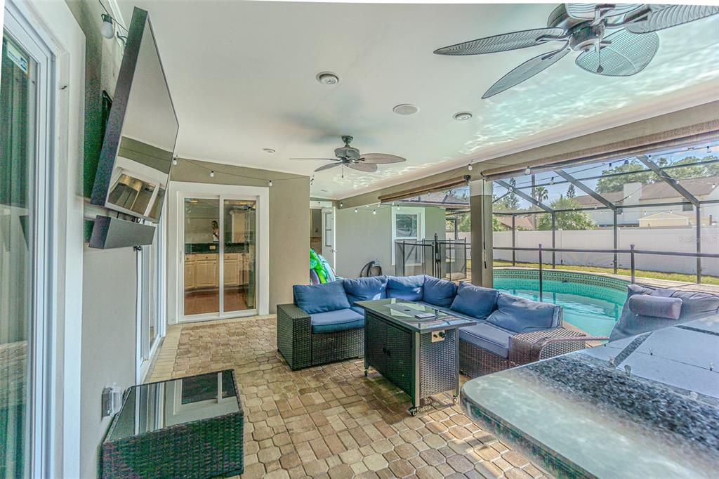 A covered outdoor patio features a sectional sofa, fire pit table, and a swimming pool — 6728 RANGER DRIVE, TAMPA, FL