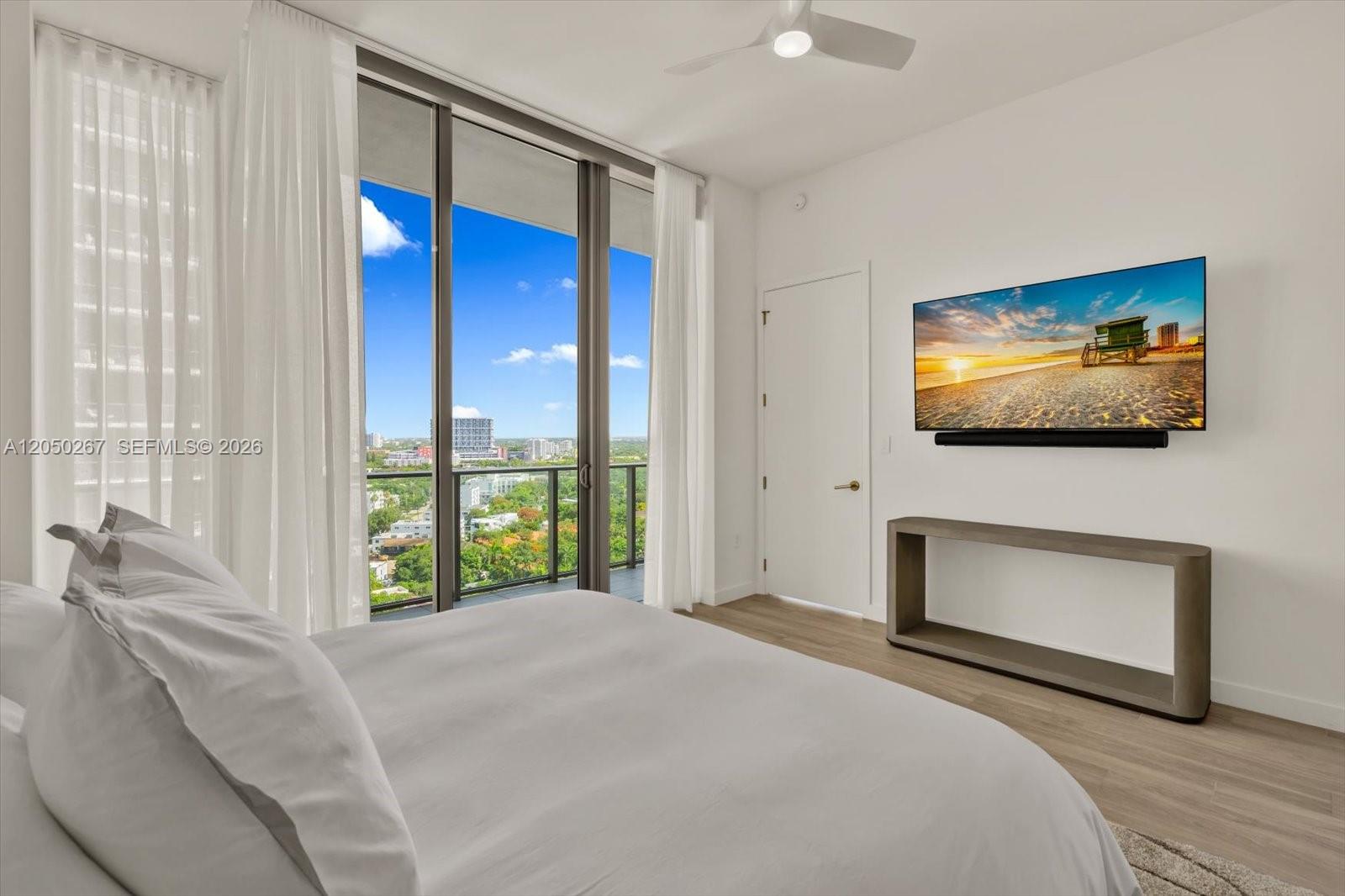 A bedroom features a bed, a wall-mounted television, and a balcony with city views — 2655 S Bayshore Dr # 1412, Miami FL 33133, MIAMI, FL