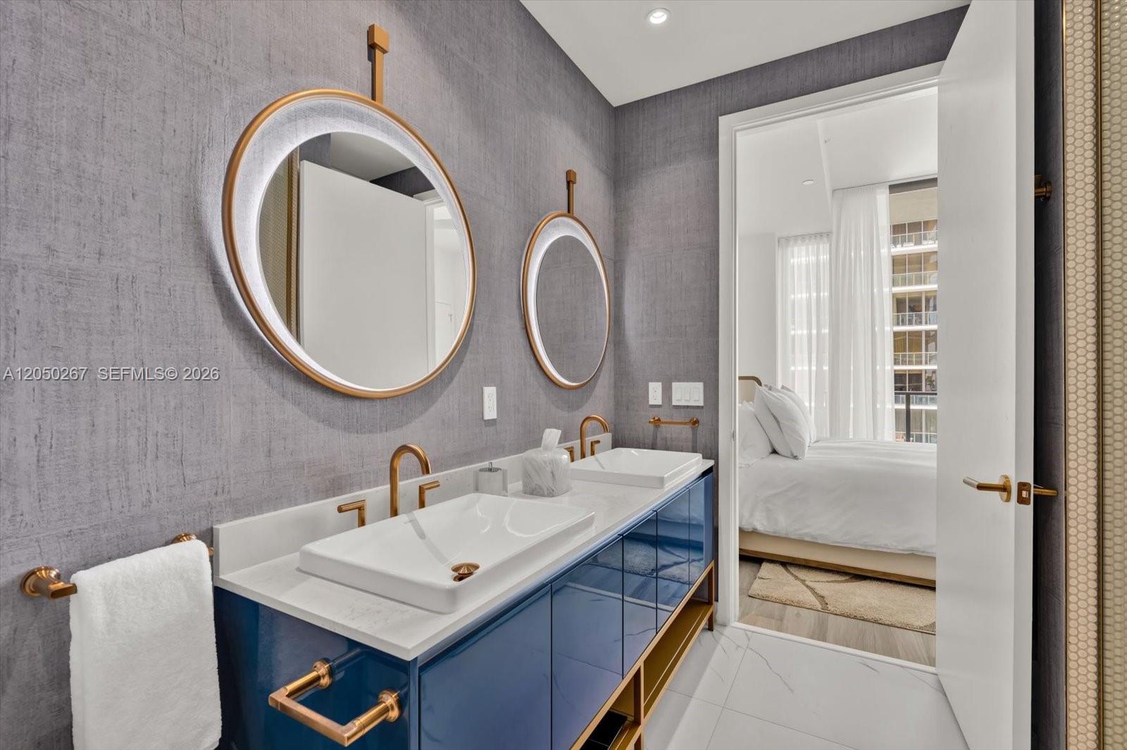 A modern bathroom features a blue vanity, dual vessel sinks, and round backlit mirrors — 2655 S Bayshore Dr # 1412, Miami FL 33133, MIAMI, FL