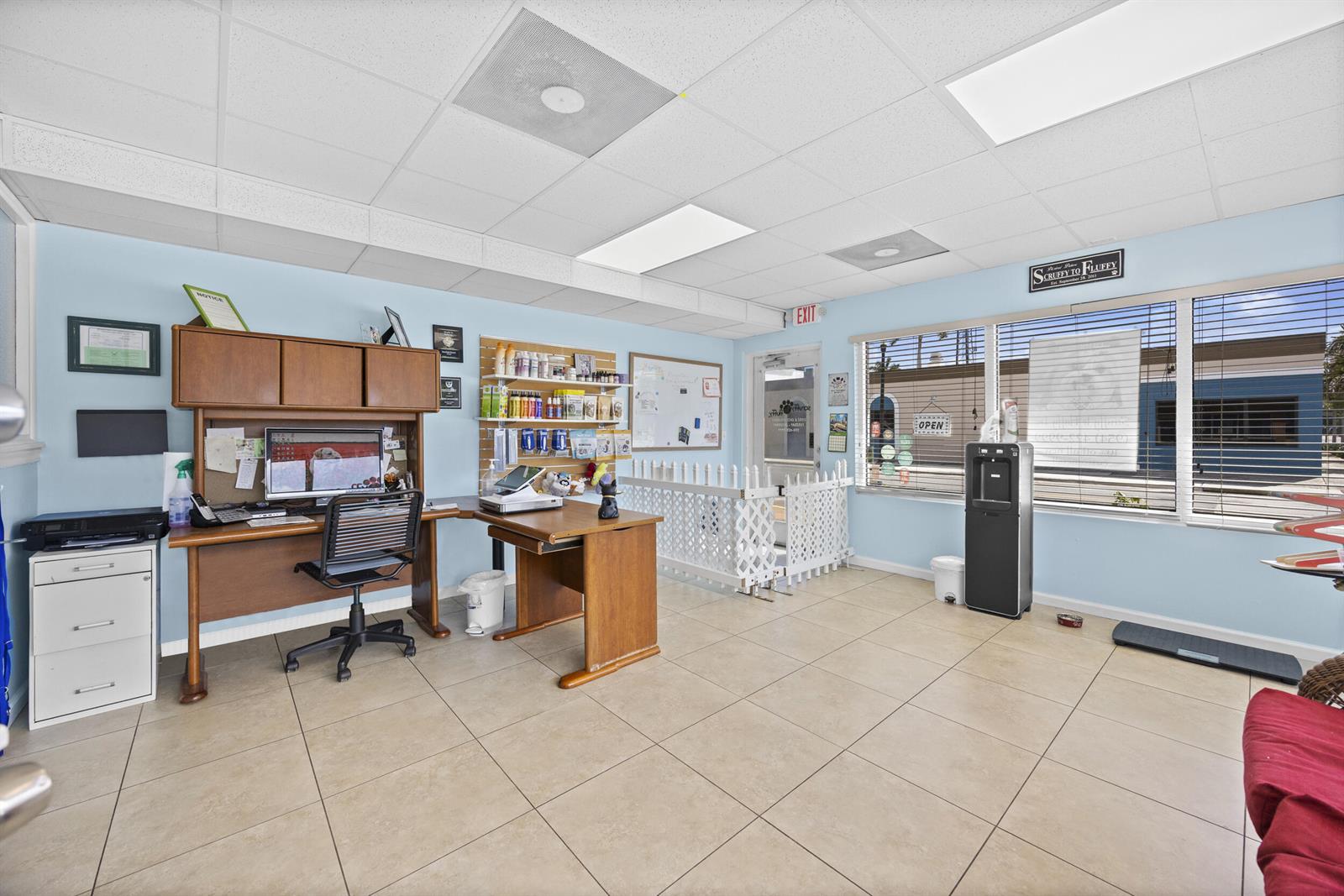 A pet grooming business office features a wooden desk, tiled floors, and a white gate — 101 NE 2nd Avenue, Deerfield Beach FL 33441, DEERFIELD BEACH, FL