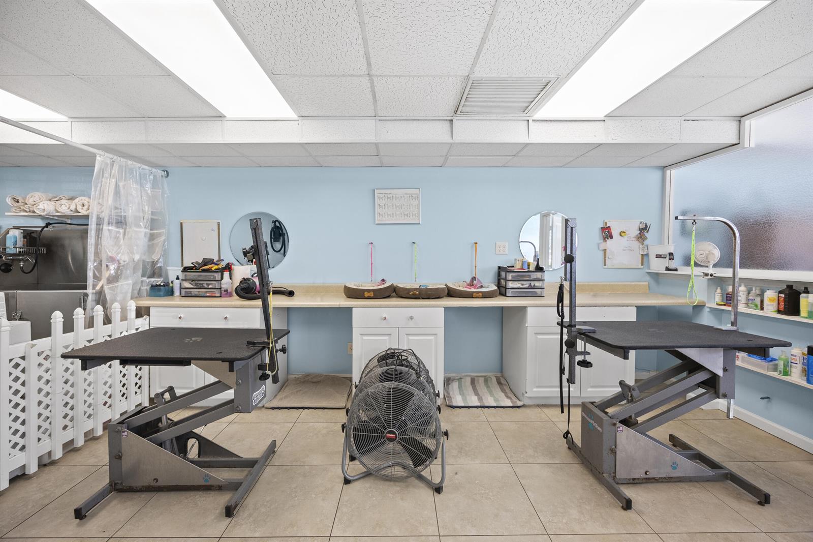 A pet grooming room features two hydraulic tables, a large floor fan, and storage cabinets — 101 NE 2nd Avenue, Deerfield Beach FL 33441, DEERFIELD BEACH, FL