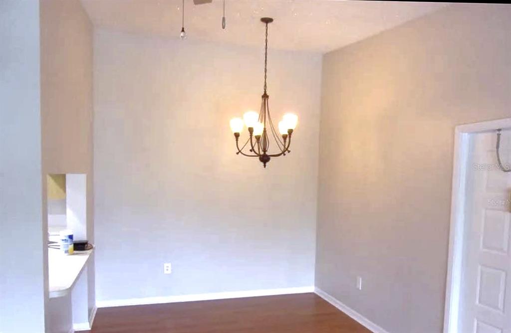 A dining area with wood flooring, a chandelier, and a pass-through window to the kitchen — 1344 PINE RIDGE CIRCLE E UNIT E3, TARPON SPRINGS, FL