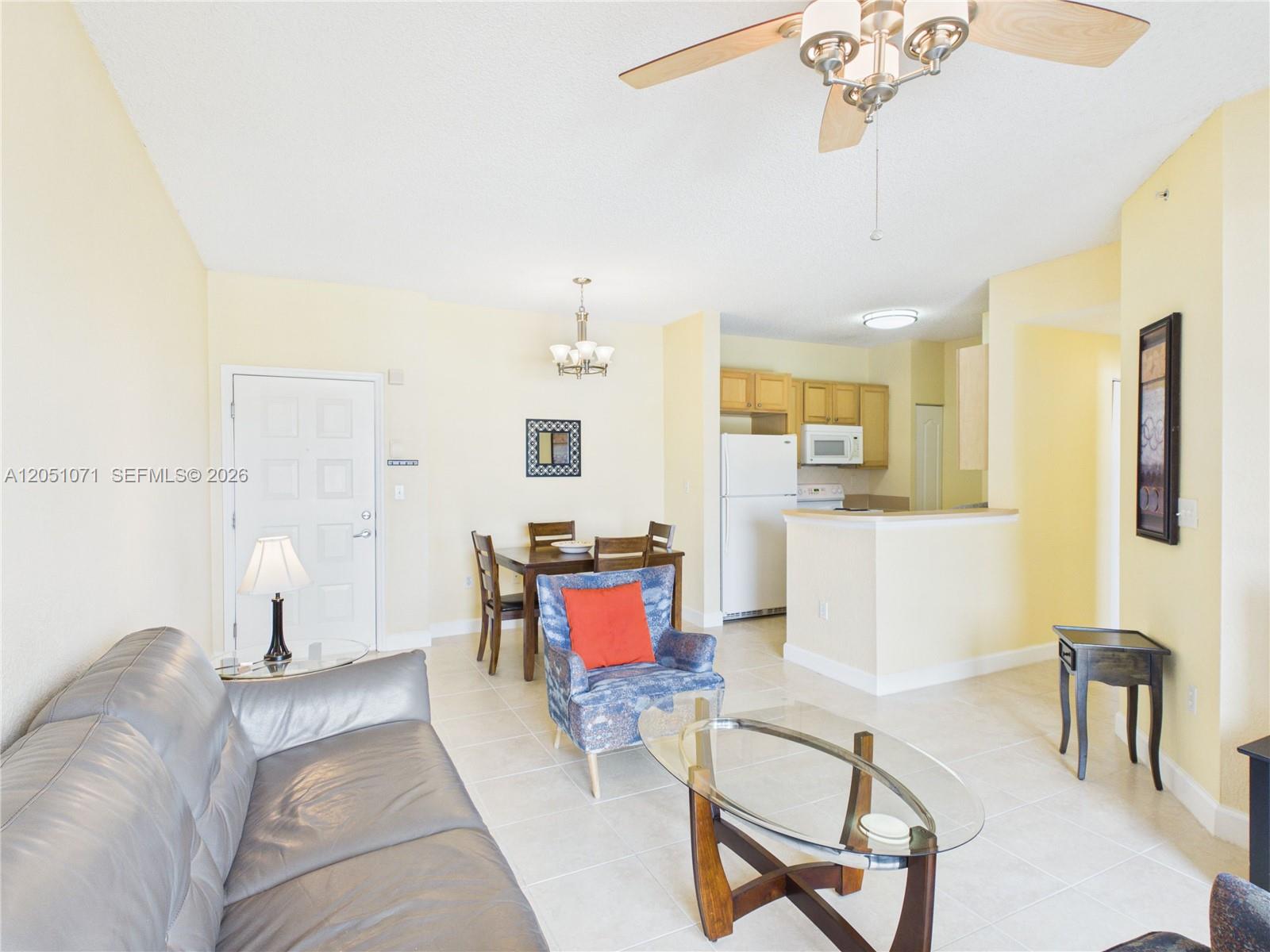 A living room and dining area feature tile flooring, a ceiling fan, and an open kitchen — 6001 SW 70th St # 502, South Miami FL 33143, SOUTH MIAMI, FL