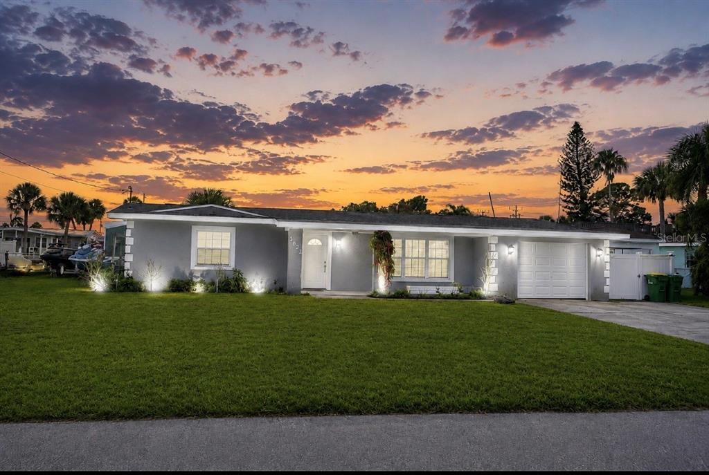 A single-story gray house with a white garage and front door at sunset — 1623 WAVECREST STREET, MERRITT ISLAND, FL