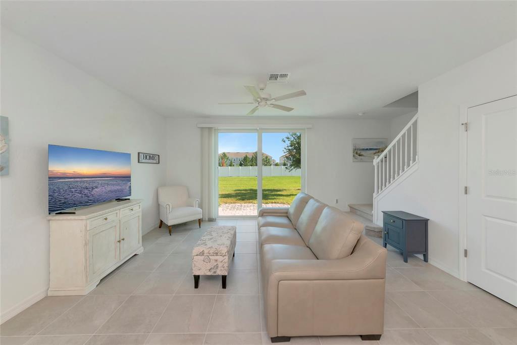 A living room features a beige sofa, a white media console, and a sliding glass door — 14251 LILAC SKY TERRACE, BRADENTON, FL