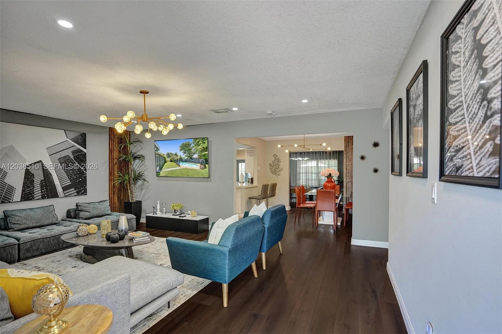A living room features dark wood floors, blue accent chairs, a sectional sofa, and artwork — 4519 Monroe St, Hollywood FL 33021, HOLLYWOOD, FL