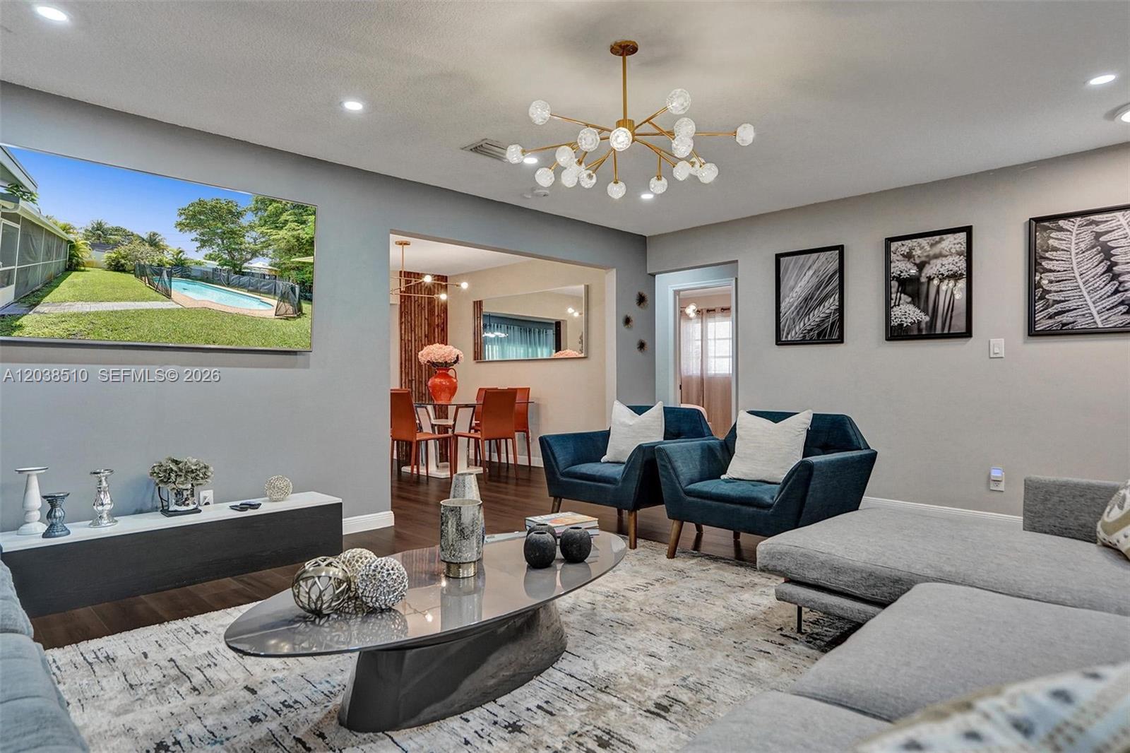 A living room features a grey sofa, two blue armchairs, and a modern chandelier — 4519 Monroe St, Hollywood FL 33021, HOLLYWOOD, FL