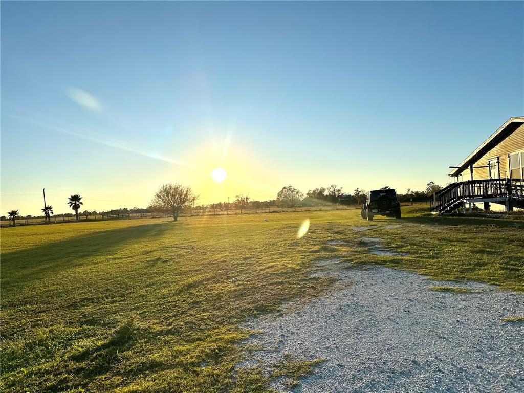 A gravel driveway leads toward a house with a deck under a bright sun — 35495 SINGLETARY ROAD, MYAKKA CITY, FL