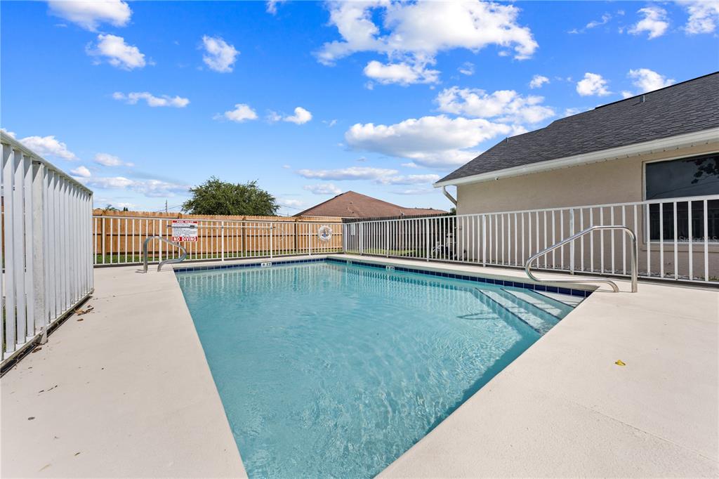 A rectangular swimming pool with a white fence sits on a concrete patio — 3078 SHINGLE CREEK COURT, KISSIMMEE, FL