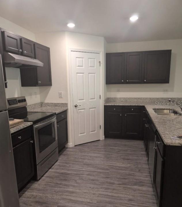 A kitchen features dark cabinets, stainless steel appliances, granite countertops, and light wood-look flooring — 1040 MELVILLE ROAD, PUNTA GORDA, FL