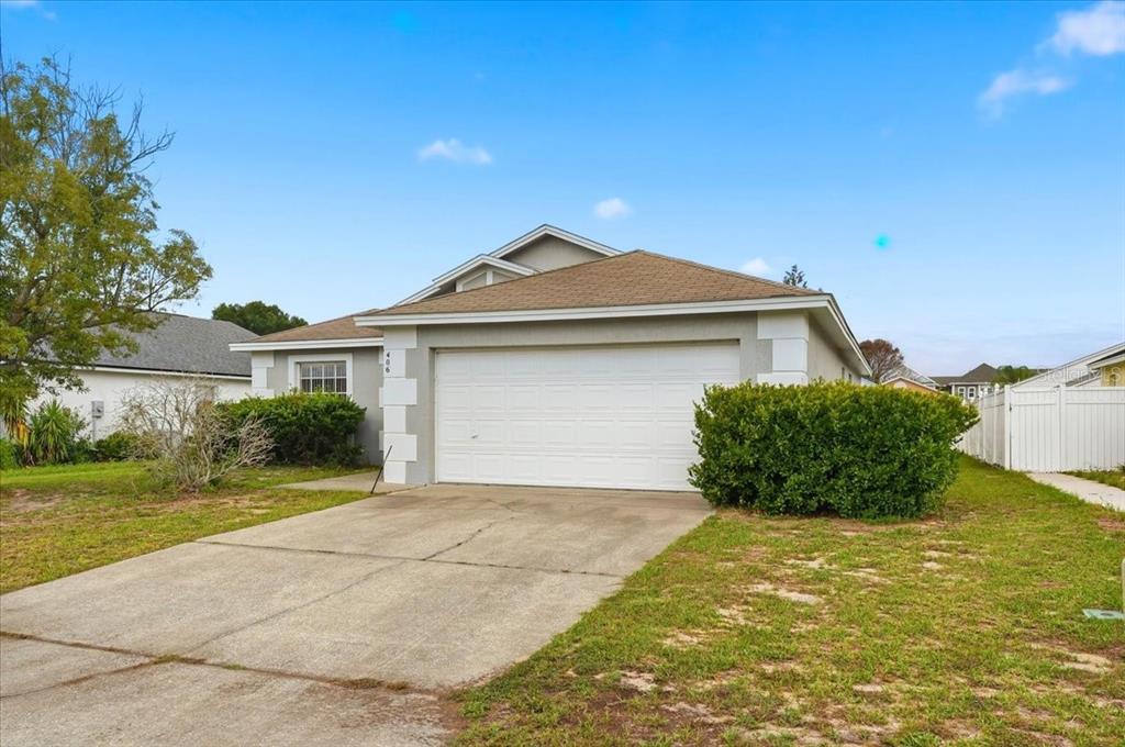 A single-story house with a white garage door, gray siding, and a brown shingled roof — 406 SAINT ANNS DRIVE, WINTER HAVEN, FL