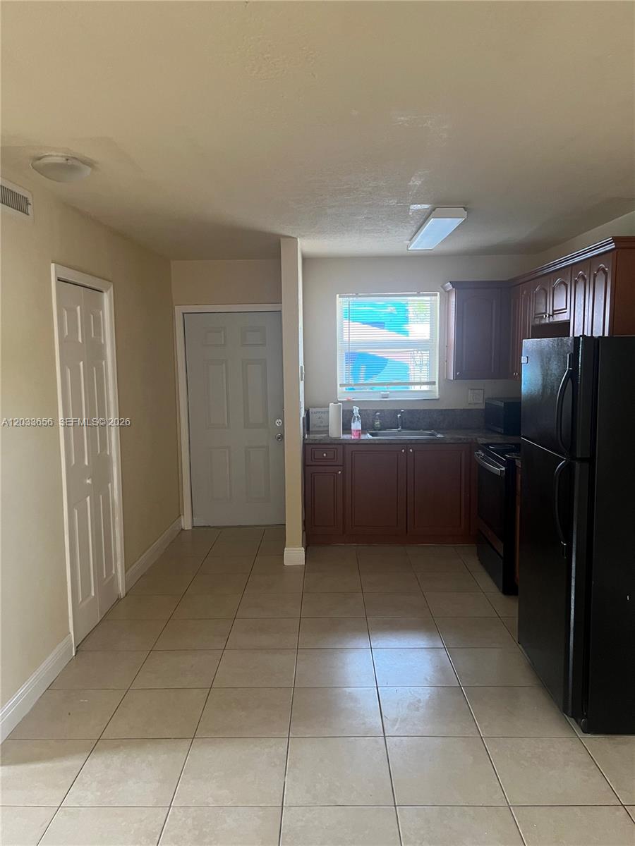 A kitchen features dark wood cabinets, black appliances, tile flooring, and a window above the sink — 5900 NW 1st Ave # 2, Miami FL 33127, MIAMI, FL