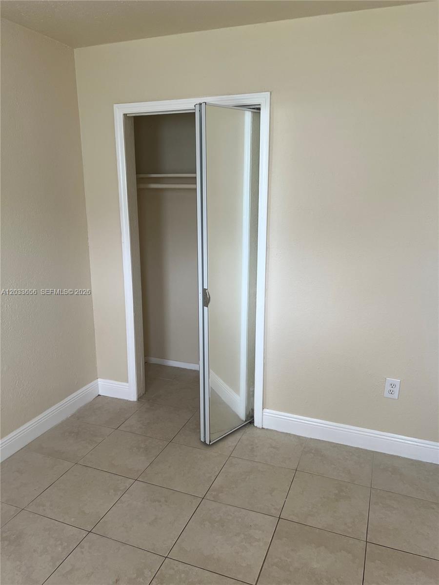 A room with beige walls, tiled flooring, and a closet with a mirrored folding door — 5900 NW 1st Ave # 2, Miami FL 33127, MIAMI, FL