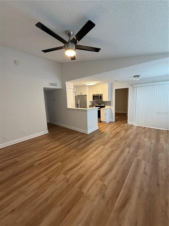 An open-concept living area features wood-look flooring, a vaulted ceiling, and an adjacent kitchen — 11520 WESTWOOD UNIT 527, ORLANDO, FL