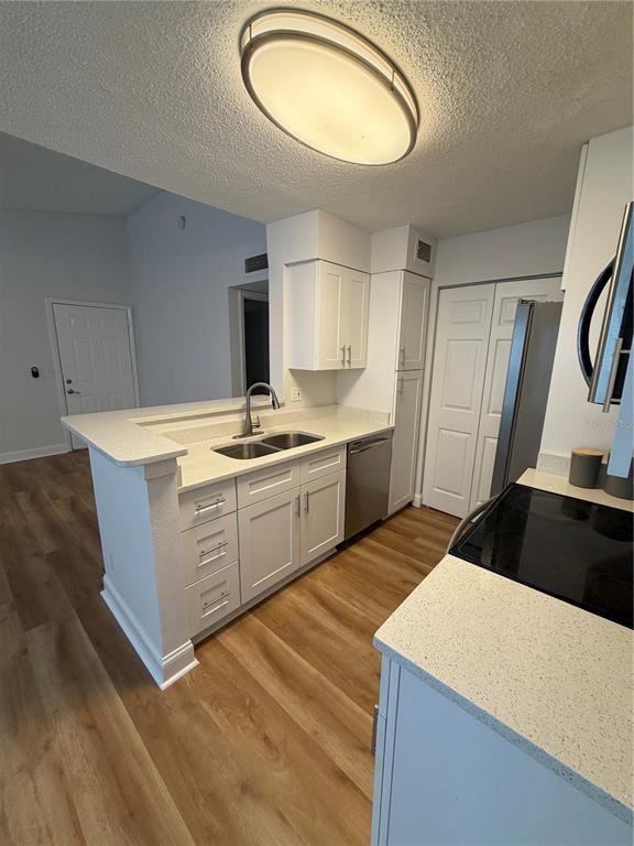 A kitchen features white cabinets, light countertops, stainless steel appliances, and wood-look flooring — 11520 WESTWOOD UNIT 527, ORLANDO, FL