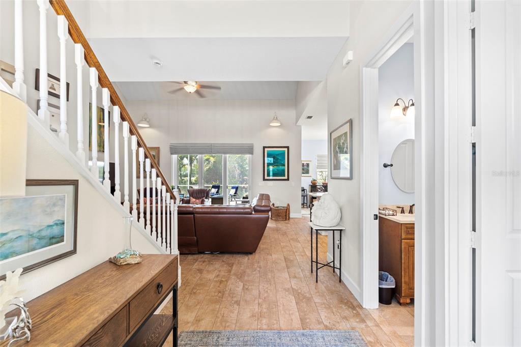 A living room with a large brown leather sectional sofa faces an open-concept white kitchen — 112 S FLORIDA AVENUE, TARPON SPRINGS, FL