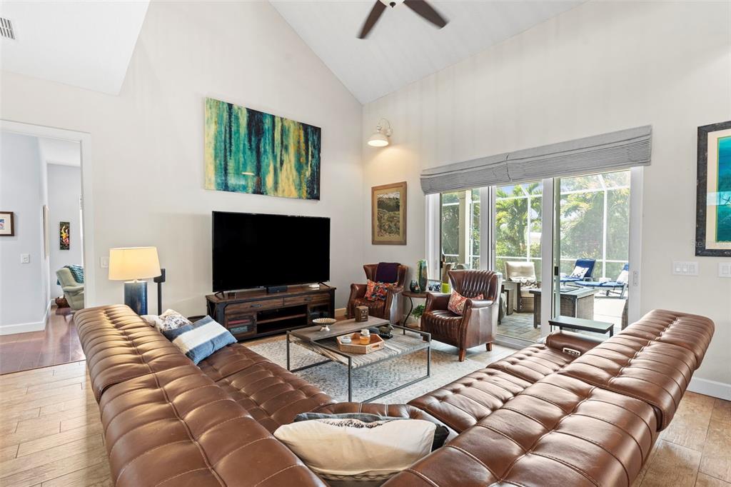 A living room features a large brown leather sectional, a television, and sliding glass doors — 112 S FLORIDA AVENUE, TARPON SPRINGS, FL