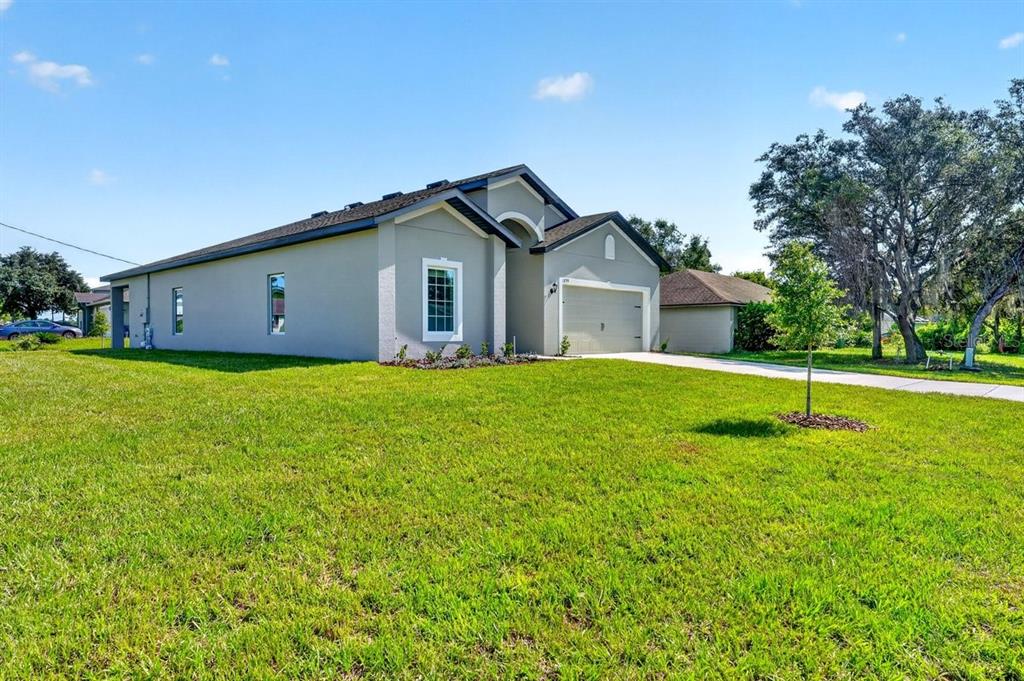 A single-story house with a gray exterior, a front-facing garage, and a large grassy lawn — 1699 WHIPPLE DRIVE, DELTONA, FL