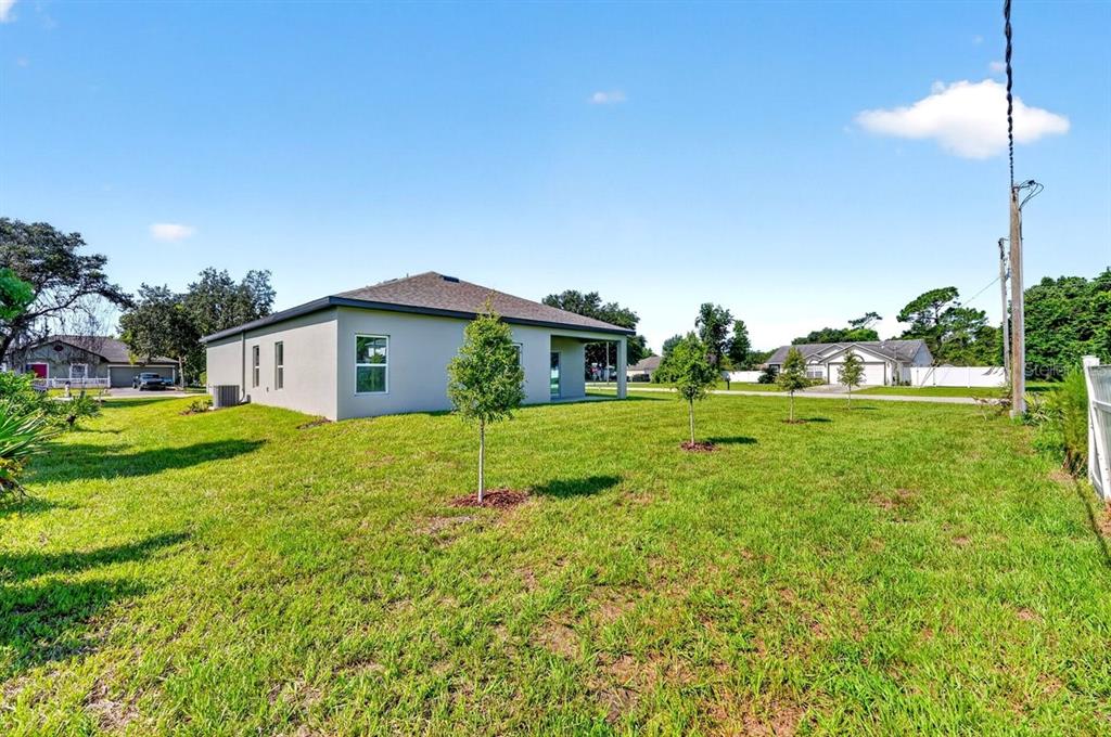 The exterior of a light-colored house with a hip roof and a large grassy yard — 1699 WHIPPLE DRIVE, DELTONA, FL