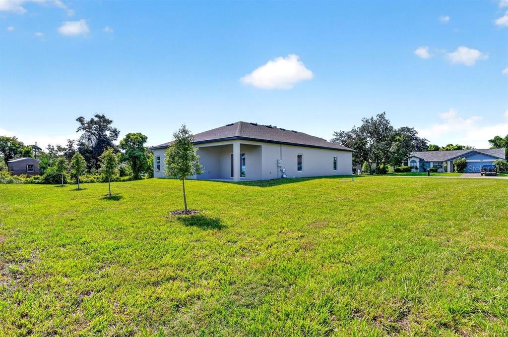 A view of the rear exterior of a single-story house with a large grassy yard — 1699 WHIPPLE DRIVE, DELTONA, FL
