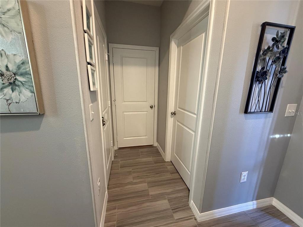 A hallway features gray walls, wood-look tile flooring, and three white interior doors — 5151 ADELAIDE DRIVE, KISSIMMEE, FL