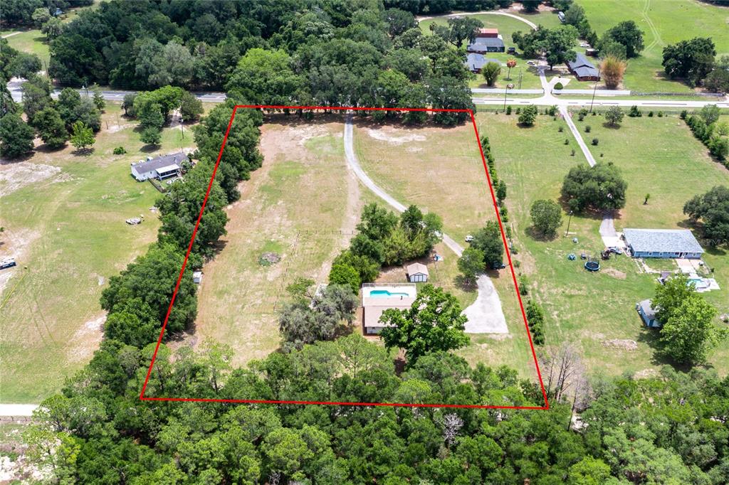 An aerial view shows a house with a pool on a large, tree-lined rural lot — 7416 SW 75TH STREET, GAINESVILLE, FL